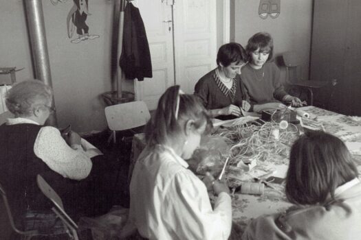 Kobiety wykonuja robotki przy długim stole.