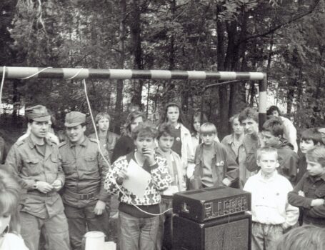 Żołnierze, młodzież i kobieta przemawiająca przez mikrofon.