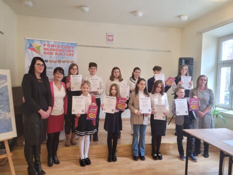 Grupa dzieci z dyplomami i nagrodami podczas konkursu recytatorskiego.