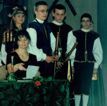 Kobieta i grupa młodzieży ubrana w stroje z epoki.