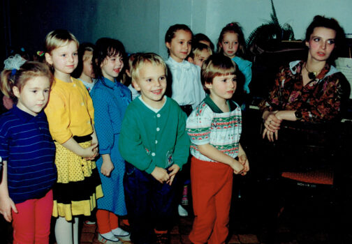 Grupa dzieci i kobieta przy pianinie