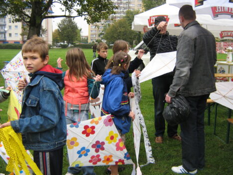 Grupa dzieci i dorosłych trzymających w rękach latawce.