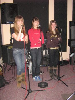 Trzy dziewczyny podczas zajęć ze śpiewu.