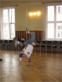 Tancerz na sali widowiskowej PMDK- wykonuje jakieś akrobacje taneczne stojąc na jednej ręce.