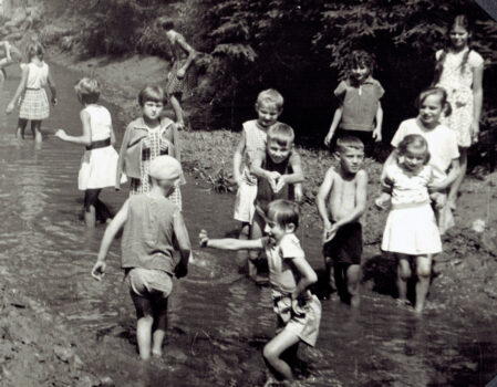 Grupa dzieciaków pluska się w wodzie.