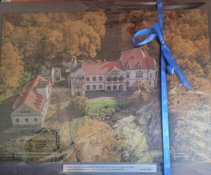 Obraz przedstawiający park i pałac w Młoszowej. Obraz przewiązany niebieską wstążką