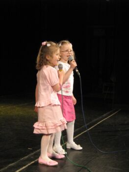 Dwie śpiewające dziewczynki w różowych sukienkach