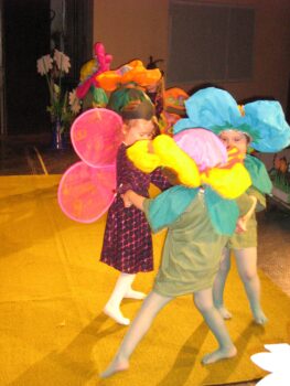 Dzieci w przebraniu kwiatów tańczą na scenie