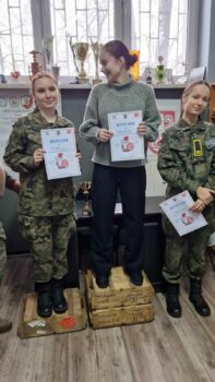 Trzy dziewczyny z pucharami i dyplomami- dwie z nich w mundurach.