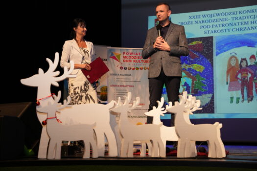 Z przodu sceny widoczne renifery ze styropianu, z tyłu Dyrektor Anita Lipnicka I Dyrektor Wydziału Edukacji, Kultury i Sportu Starostwa powiatowego w Chrzanowie. Na ekranie banerek Konkursu.