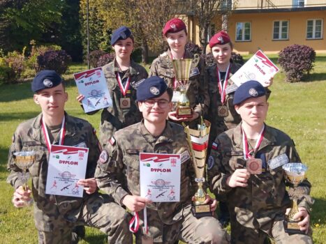 Trzech chłopaków i trzy dziewczyny w mundurach z pucharami i dyplomami.