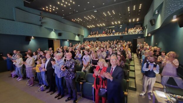 Widok na publiczność w TCK po premierze musicalu. Wszyscy stoją i klaszczą.