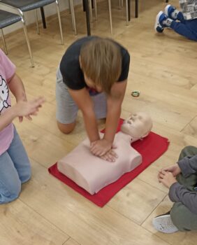 Młody człowiek ćwiczy uciski na fantomie.
