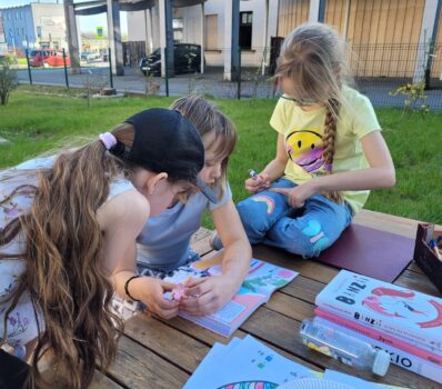 Dzieci w ogrodzie PMDK podczas zajęć języka polskiego. Czytają i tworzą treści.