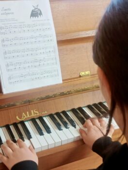 Dziecko podczas zajęć nauki gry na pianinie.