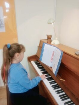 Dziecko podczas zajęć nauki gry na pianinie.