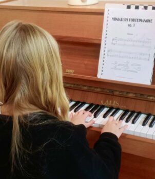 Dziecko podczas zajęć nauki gry na pianinie.