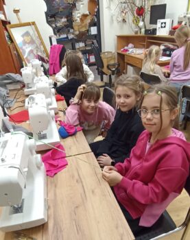 Grupa przy maszynach do szycia podczas zajęć.