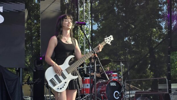 Młodzież podczas występu na wielkiej scenie Dni Trzebini 2025. Dziewczyna gra na gitarze.